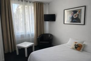 a hotel room with a bed and a chair and a window at Vieille tour Hotel centre Rouen in Rouen