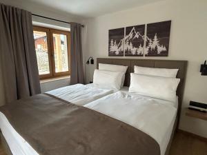 a bedroom with a bed with white sheets and a window at Landhaus Sonnenwang in Pfronten