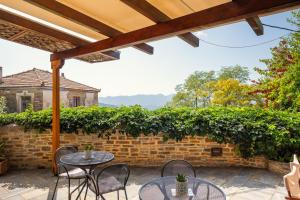a patio with tables and chairs and a brick wall at xenonas ton xromaton - Guest house of colors in Lafkos
