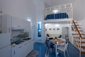 a kitchen with white cabinets and a table with a dining room at Alfieri Rooms - Amalfi coast in Atrani