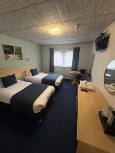 a hotel room with two beds and a table at Sandown Park Lodge in Esher