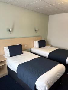 two beds sitting next to each other in a room at Sandown Park Lodge in Esher
