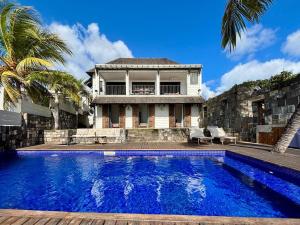 a villa with a swimming pool in front of a house at Villa Canonniers - Pieds dans l'eau à Grand Baie in Pointe aux Canonniers