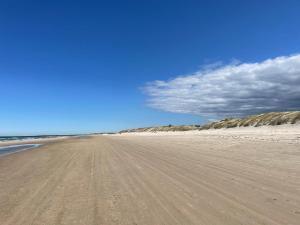 an empty beach with a blue sky and clouds at God Plads Og God Beliggenhed I Løkkenshus in Løkken +9 photos