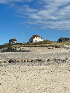 a beach with houses on top of a hill at God Plads Og God Beliggenhed I Løkkenshus in Løkken