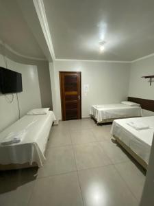 a hotel room with two beds and a television at Hotel Acauã in Campo Mourão