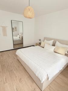 a white bedroom with a large bed and a mirror at R Lodge in Winterberg