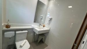 a white bathroom with a toilet and a sink at Rincão Resort in São Paulo