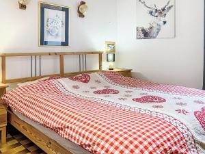 a bedroom with a bed with a red and white blanket at Apartment Les Grangettes by Interhome in Auberson