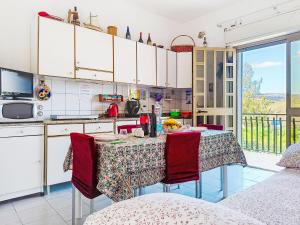 a kitchen with a table with red chairs and a kitchen with white cabinets at Apartment Clara by Interhome in Fondachello