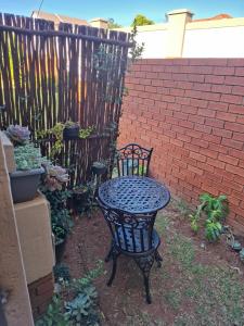 a black table and chair next to a brick fence at Cozy City Studio Escape in Centurion