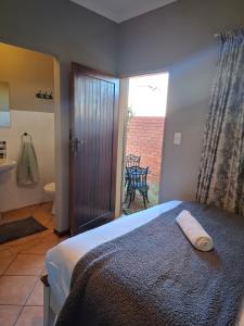 a bedroom with a bed and a bathroom with a window at Cozy City Studio Escape in Centurion
