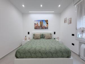 a white bedroom with a large bed with a green bedspread at B&B Sabò in Bologna