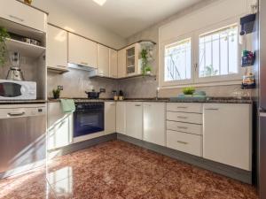 a kitchen with white cabinets and a tile floor at Holiday Home Estrella by Interhome in Riumar