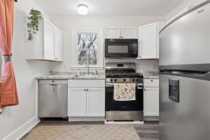 a kitchen with white cabinets and a stainless steel refrigerator at 3BR Home Across from Como Lake - Aspen in Saint Paul