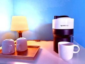 a coffee maker and two cups on a table at La Ferme des Roses in Tournai