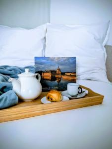 a tray with a tea pot and a croissant on a bed at La loge Diane, à deux pas du château et son jardin à la française in Chantilly