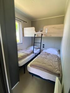 two bunk beds in a small room with a window at camping des crocs in Saint-Quentin-en-Tourmont
