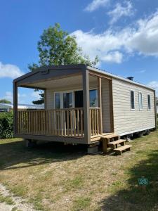 a mobile home with a deck on a field at camping des crocs in Saint-Quentin-en-Tourmont