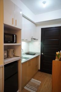 a kitchen with white cabinets and a black door at The Storeys - Mesaverte Residences CDO in Pontud