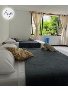 two beds with pillows on them in a bedroom at Arya Land Yoga Hostel in Cali