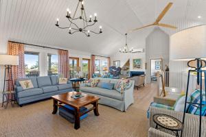 a living room with blue furniture and a chandelier at Boots to Beach in Duck