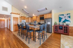 a kitchen with a island with bar stools at Paradise Found - Nags Head MP 16.5, Oceanfront, Ocean & Sound Views, Pool, Hot Tub, Pets OK in Nags Head +79 photos