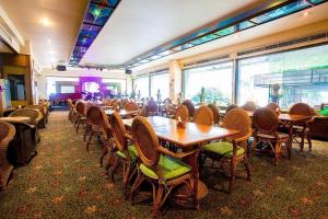 a restaurant with wooden tables and chairs in a room at Pailyn Hotel Phitsanulok in Phitsanulok