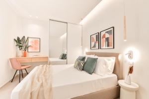 a white bedroom with a bed and a chair at Elan Suites Preveza in Preveza
