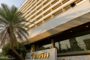 a building with a palm tree in front of it at Pailyn Hotel Phitsanulok in Phitsanulok