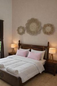a bedroom with a bed with pink pillows and two lamps at Villa Stella Garden in Senggigi