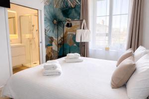 a bedroom with a white bed with towels on it at La Villa Blanche Appart hôtel in Salles