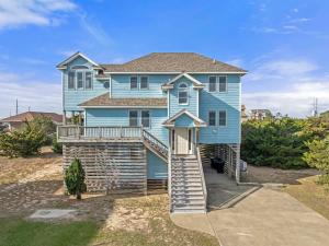 a blue house with a staircase leading up to it at Sea Spray in Waves