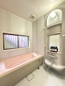 a bathroom with a pink bath tub and a window at 禅 宮島 一棟貸し 最大6名 ダブルベット3台 2階建の1棟貸しホテル in Hatsukaichi +20 photos