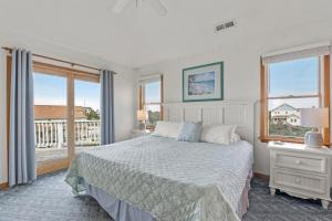 a white bedroom with a bed and a balcony at Sea Spray in Waves +39 photos