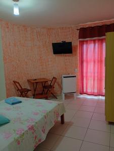 a living room with a table and a television on the wall at Pousada Real in Itamonte