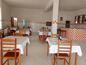 a restaurant with white tables and wooden chairs at Pousada Real in Itamonte