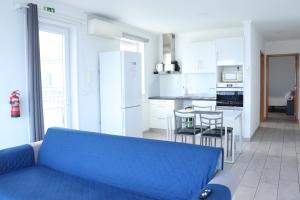 a living room with a blue couch in a kitchen at Faial Marina Apartments 2 in Horta