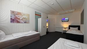 a hotel room with two beds and a tv at J&R Gästezimmer Kassel in Niestetal