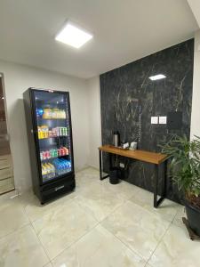 a drink refrigerator in a room with a table at Hotel Acauã in Campo Mourão