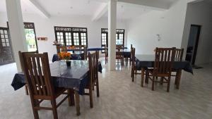 a dining room with a table and chairs and a room with windows at Stay Suite in Mahiyangana