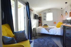 a bedroom with a bed and a yellow chair at Beautiful shepherd’s hut in Newmarket
