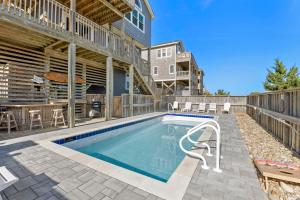 a swimming pool with a patio and a building at HIWA03: Lands End in Waves