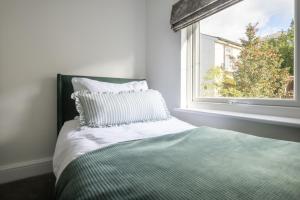a bed with a pillow sitting next to a window at The Rosemont in Royal Tunbridge Wells
