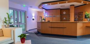 an office lobby with a reception desk and a couch at Hotel Arkadia in Friedrichsdorf