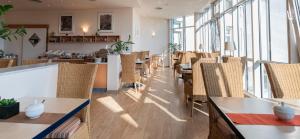 a restaurant with tables and chairs and windows at Hotel Arkadia in Friedrichsdorf