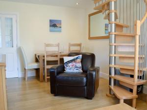 a living room with a chair and a spiral staircase at Ghillie Cottage in Cockermouth