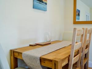a wooden table with a wine glass on top of it at Ghillie Cottage in Cockermouth