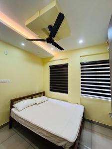 a bedroom with a bed with a ceiling fan at panakkal tower in Guruvāyūr