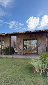 a house with a hammock in front of it at Pousada Vila Assu in Ceará-Mirim